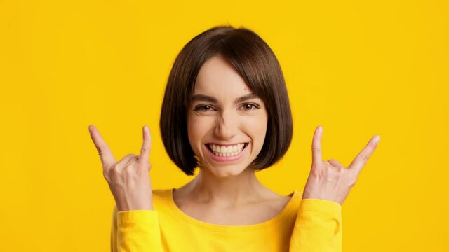 Lady Making Sign Of The Horn Rock Gesture, Yellow Background