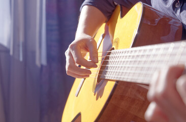 Closeup of a boy playing guitar by the window, blue background, depth of field