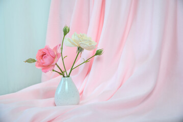 Obraz premium Pink curtain, bright red and white roses in a white vase, copy space