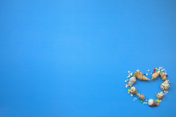 Heart-shaped pattern made of conches and colorful pebbles, copy space