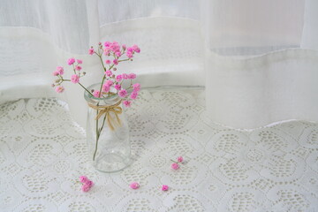 Close-up of red flowers on white lace tablecloth, copy space