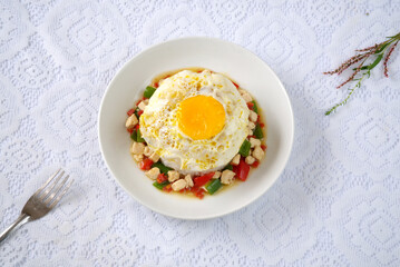 Top view of rice bowl with egg, chicken, green and red peppers; a fork