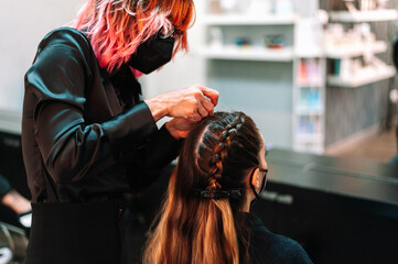 Fototapeta premium Hairdresser make French braid in beauty salon.