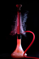 hookah with glass flask and earthenware bowl with smoke on black background.Traditional oriental rest for relaxation