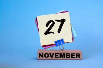 November 27th. Day 27 of November month, calendar on workplace with blue background. Autumn time. Empty space for text