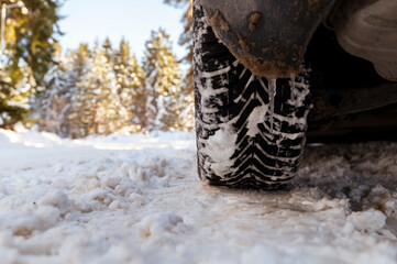 Car tires on winter road covered with snow.
