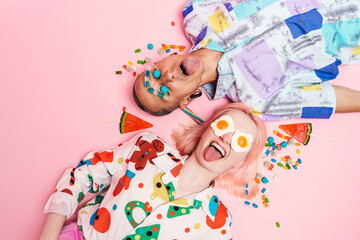 Young couple making fun with candies while lying on floor