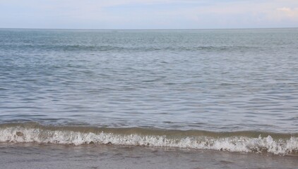 simple background of calm sea with low waves on the sandy shore of the beach