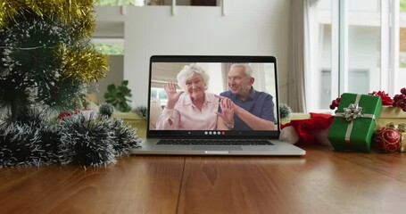 Smiling senior caucasian couple waving on christmas video call on laptop - Powered by Adobe