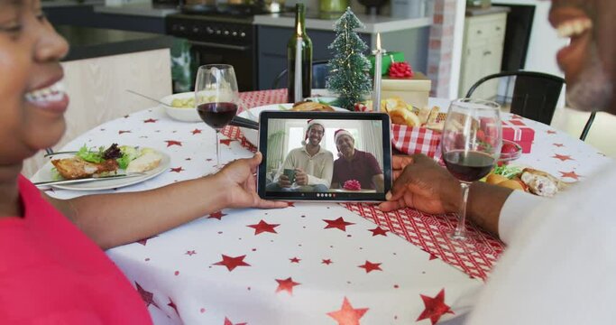 Smiling african american couple using tablet for christmas video call with family on screen