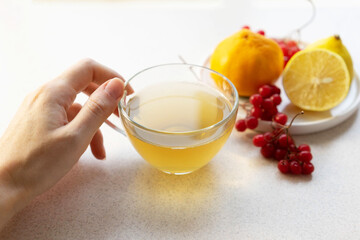 female hand holding a cup of tea on the background of a plate with berries and citrus. The concept of natural teas, maintenance of immunity, antioxidants, vitamin c