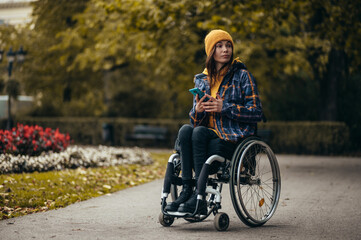 Woman in wheelchair using a smartphone while out in the city park