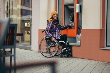 Woman in wheelchair using credit card and atm machine