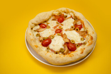 Appetizing homemade pizza with cheese and tomatoes on yellow background with copyspace