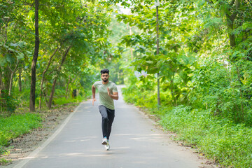 Fototapeta premium Young man running in the park at morning, also known as jogging or morning walk