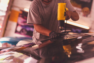 Car specialist tinting film for car glass with hairdryer.