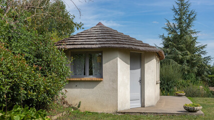 Small hut with a grey door and grass roof