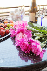 Pink peony rose flower, peaches, cherries and sweet strawberries on a tray. Beautiful Still life on the terrace on the table. top view.