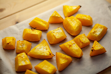 Pumpkin slices baked on a baking sheet in the oven. Homemade food, Vegan food, Healthy food, orange vegetables on a baking sheet and napkin, baked rustic vegetables, pop art, dessert during a diet
