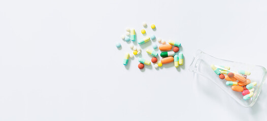 pills and science experiments on white background, White medicine capsules spill out from transparent bottle,Prescription pill bottle spilling pills on to surface isolated on a white background.