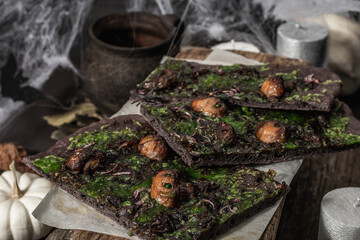 Halloween concept food. Flatbread or pizza with squid Ink, green cheese, mushrooms and purple onion