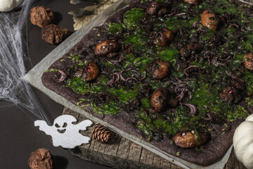 Halloween concept food. Flatbread or pizza with squid Ink, green cheese, mushrooms and purple onion