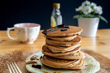 Healthy buckwheat pancake stack with dark chocolate, maple syrup and halvah on a decorative plate....