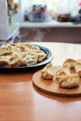 Uncooked russian pelmeni on cutting board and ingredients for homemade pelmeni on white table. Process of making pelmeni, ravioli or dumplings with meat