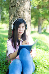 Asian woman reading a book and smiling in the park,Satisfied asian woman reading a book in a park
