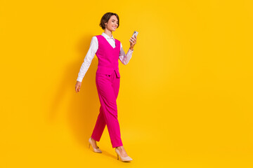 Full size photo of cool young brunette lady go look telephone wear pink suit stilettos isolated on yellow background