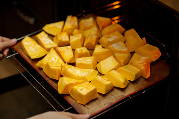 Pumpkin slices baked on a baking sheet in the oven. Homemade food, Vegan food, Healthy food, orange vegetables on a baking sheet and napkin, baked rustic vegetables, pop art, dessert during a diet