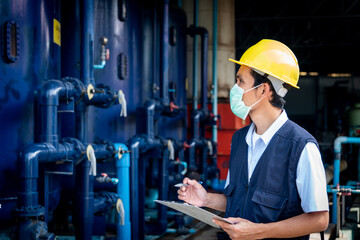 Portrait of male factory worker looking at equipment of machines in modern factory