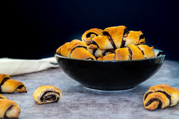 Pile of freshly baked rugelach pastries filled with chocolate, placed in a bowl. Delicious traditional Jewish rolled cookies or treat made with healthy ingredients. Golden shiny color, soft texture.