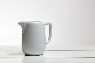 Milk jug on wooden background. Porcelain sauce boat, pitcher, creamer or ceramic gravy boat