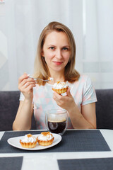 A young girl drinks black coffee from a transparent mug for breakfast and eats cakes, top view.