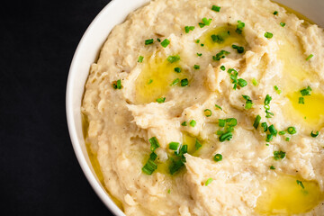 Garlic Mashed Potatoes in a Serving Bowl: A large bowl of whipped potatoes topped with chives and melted butter