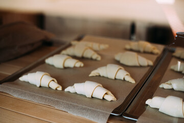raw croissants on parchment paper prepared for baking