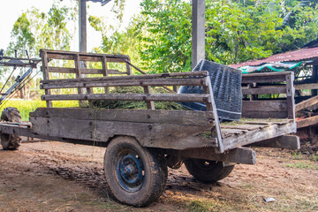An agricultural tractor-trailer made of wood parked on a farm