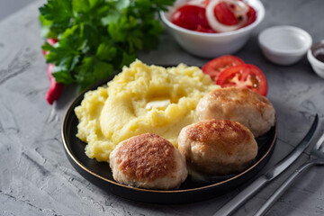 A hearty lunch for the family: mashed potatoes and a meat patty on a plate on a wooden table. Close-up