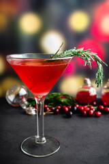 Holiday Gin and Tonic Garnished with Frosted Rosemary: A cranberry and gin cocktail served in a martini glass garnished with a sugared rosemary sprig