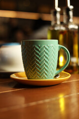Green mug on a wooden table against a grunge background, side view of hot tea on the table in a cafe, lunch or dinner time, table setting in a restaurant