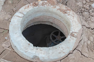 Motage of a concrete sewer well with a gate valve at a construction site. Close-up. Late communications.