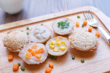 Close-up, Coconut rice cakes, Topped with a variety of toppings carrot to, corn, green onions, and taro on a wooden plate. One of the most popular street foods in Thailand, Selective focus