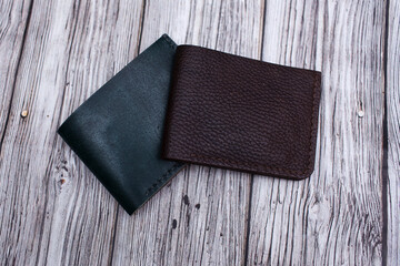 Handmade products made of natural brown and green leather. leather wallet for cash. Leather goods for men and women on a wooden background. Top view