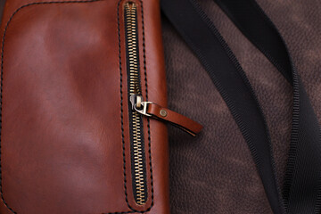 open women's brown leather bag on a brown background, top view. Products made of genuine soft leather. Waist bag, shoulder bag. Zipper bag