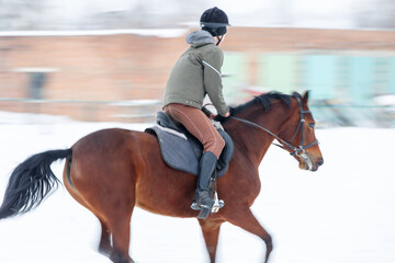 Young horse rider training on the field in winter.