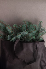  Bouquet made of coniferous, fir tree branches in bag on gray background. Christmas composition. New year concept. Top view, copy space.