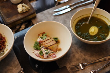 Green soup with spinach and a warm salad with chicken is on the table in the restaurant. The visitor is going to eat hot and healthy soup. Table setting. Lockdown and quarantine
