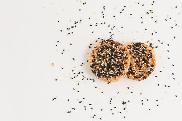 Two pieces of rice cracker mixed grains topping with Black sesame seed and White sesame seed on white background. Top view.