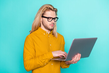 Photo of young guy focused look read chat type email laptop work programmer isolated over turquoise...